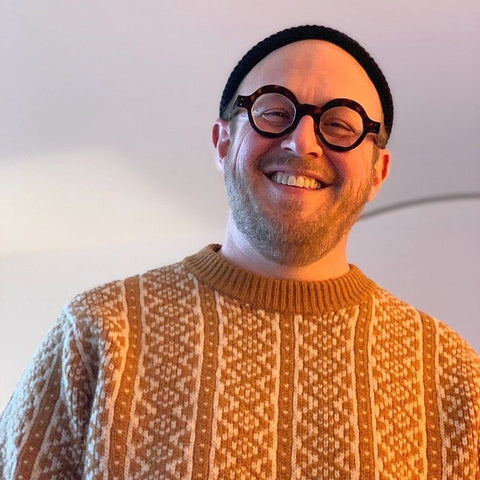 picture of happy customer in a orange sweater and black hat wearing bold round tortoise glasses | eyedeals eyewear